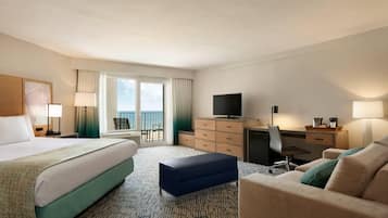 A hotel room with a large bed, a desk, a television, and a balcony with a view.