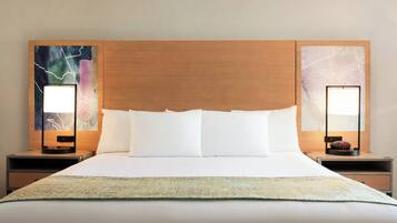 Una habitación de hotel con una cama grande, dos mesitas de noche y un cuadro abstracto en la pared.