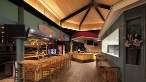 A bar area with wooden furniture, a surfboard decoration, and a large ceiling with a wooden design. - Surfbreak Virginia Beach Oceanfront, an Ascend Collection Hotel (Virginia Beach)