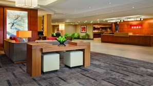 Um lobby moderno de hotel com balcão de recepção, área de estar e espaço para refeições.