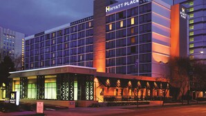 Um hotel de vários andares com uma placa chamativa da "Hyatt Place", janelas grandes e uma área de entrada coberta.