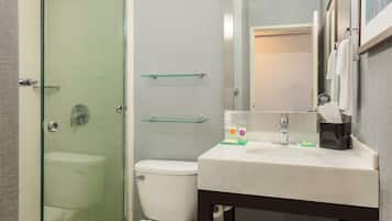 A bathroom with a glass-enclosed shower, a white toilet, a sink with a mirror, and a towel rack.