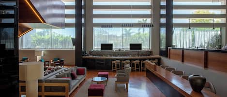 Amplia sala de estar con una larga mesa de madera, asientos cómodos y una zona de bar con un gran ventanal.