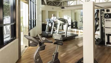 A gym with exercise equipment, large windows, and a view of the outdoors.