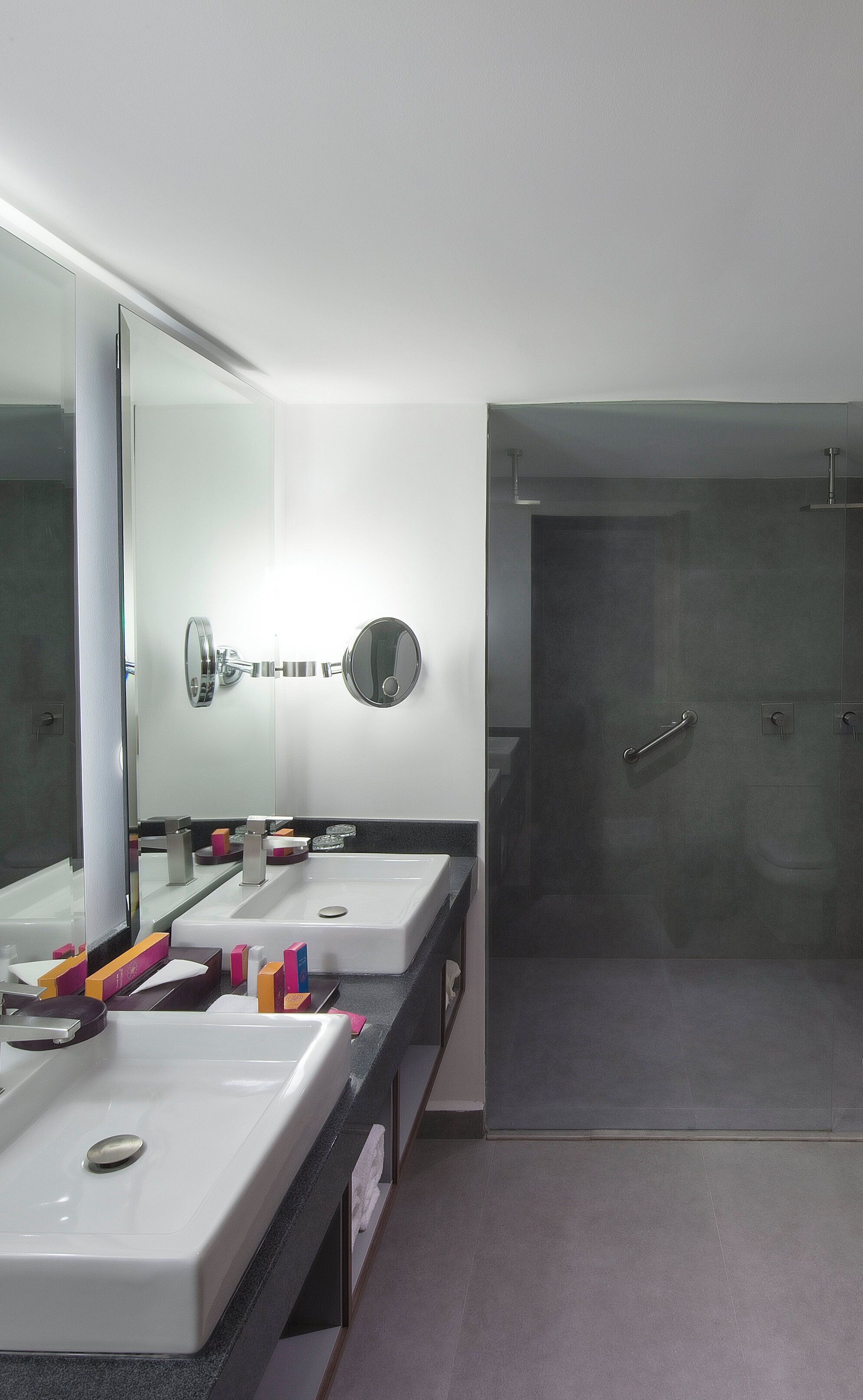 Ein modernes Badezimmer mit zwei Waschbecken, einem großen Spiegel und einer Duschkabine.