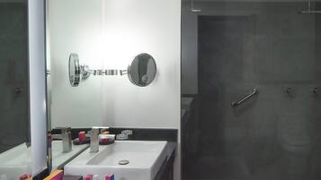 Ein modernes Badezimmer mit zwei Waschbecken, einem großen Spiegel und einer Duschkabine.