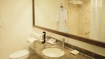 A hotel bathroom with a large mirror, a sink, a toilet, and a shower area.