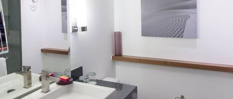 Ein modernes Badezimmer mit einem großen Waschbecken, einem Spiegel und einer Toilette.