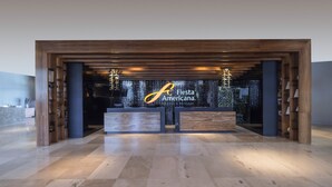 Un área de recepción con un mostrador de madera y un letrero que dice "Fiesta Americana".