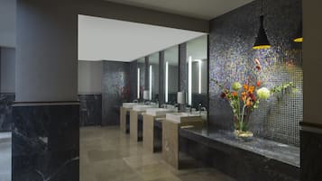Bathroom features three sinks, a large mirror, and pendant lights.
