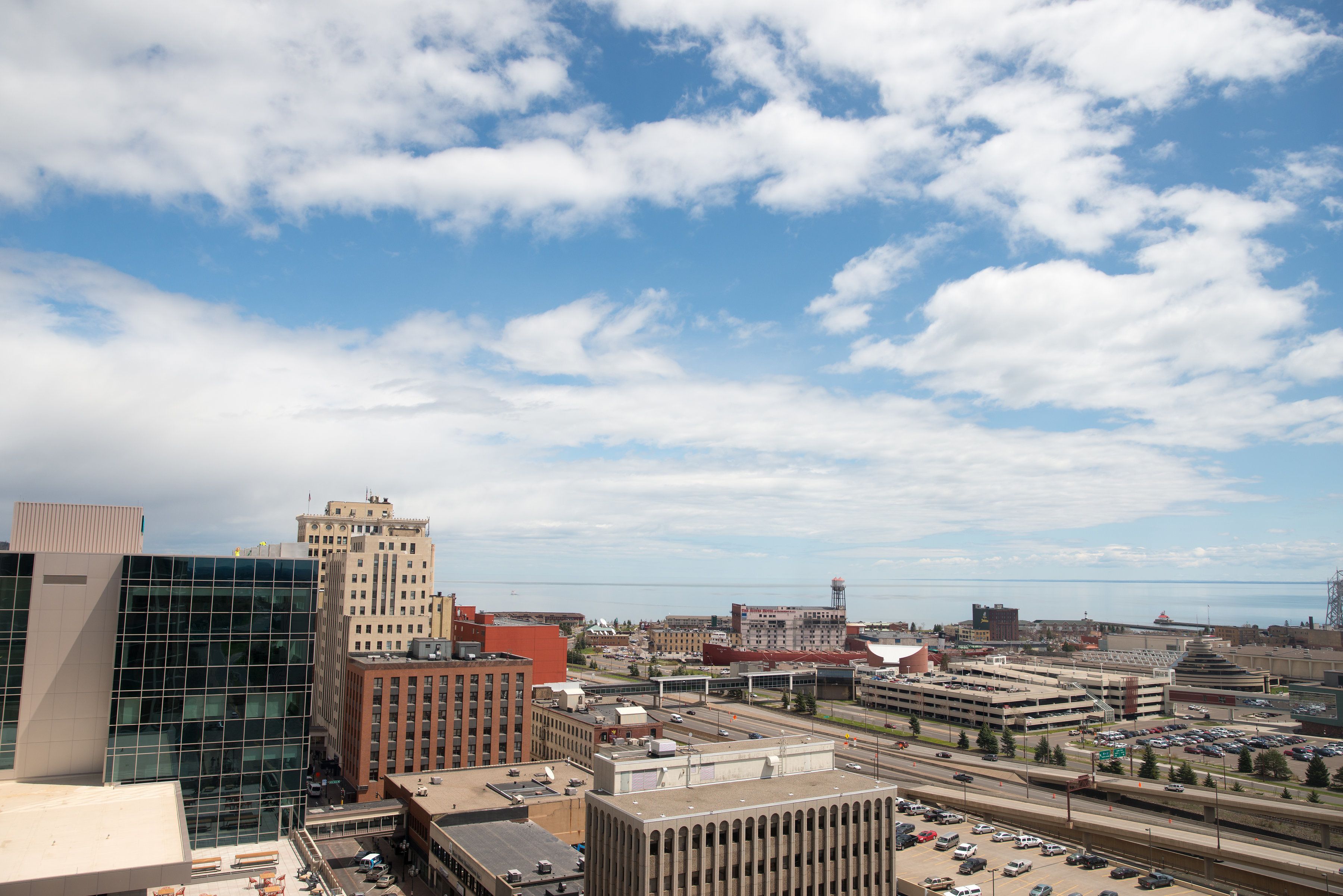 A cityscape with modern buildings, a parking lot, and a clear sky.