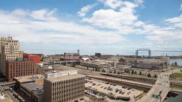 A cityscape with a parking lot, buildings, and a bridge in the background.