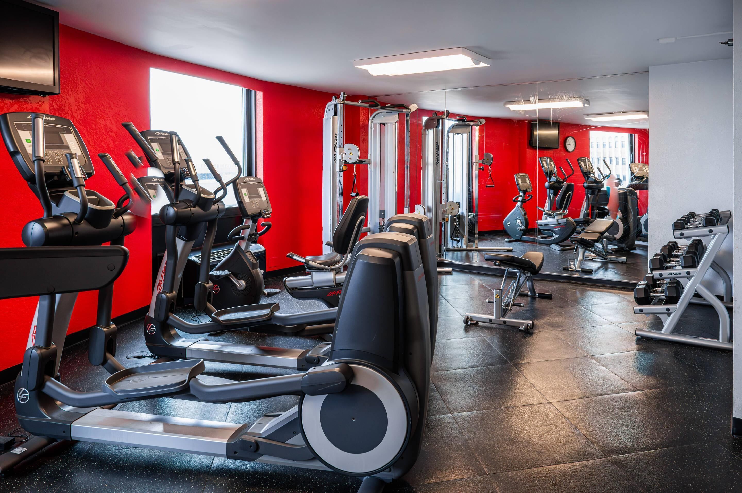 Een fitnessruimte met loopbanden, elliptische trainers en gewichthefrijsapparatuur.