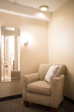Relax in comfort with a cozy armchair and full-length mirror in this inviting room.