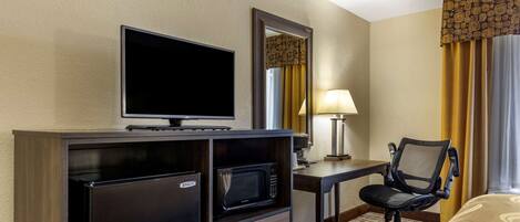 A hotel room with a bed, a desk with a chair, a television, a microwave, and a refrigerator.