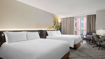 Une chambre d’hôtel avec deux lits, un bureau, une chaise et une grande fenêtre avec des rideaux.