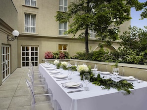 A long outdoor dining table set with white tablecloths, clear chairs, and floral centerpieces. - Novotel Toronto Centre (Toronto)