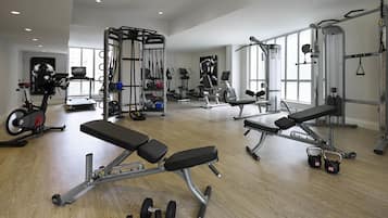 Uma academia com equipamentos de ginástica, bancos e pesos.