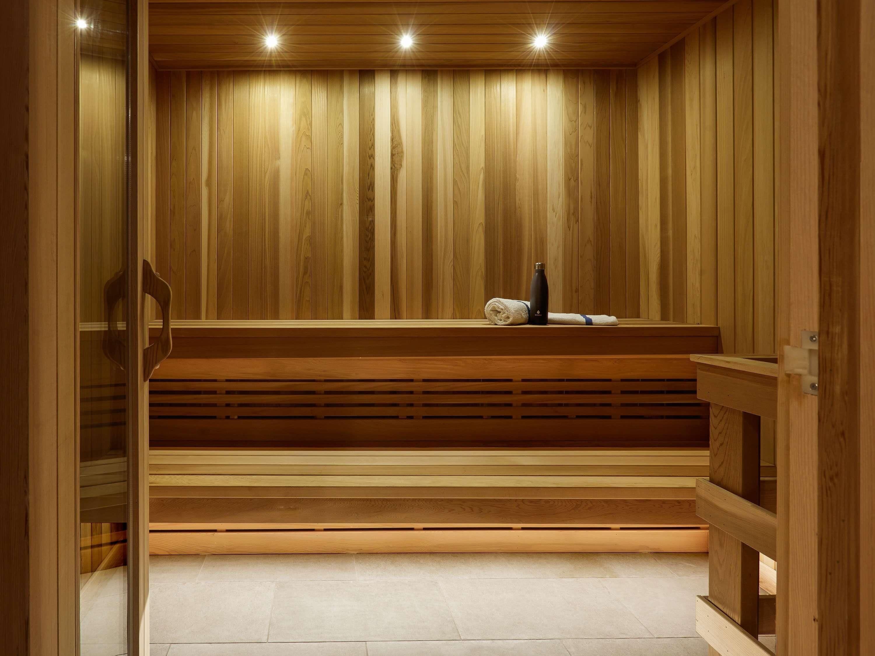 A wooden sauna with benches, a towel, and a bottle.