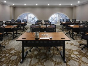 Una sala conferenze con un grande tavolo, sedie e una caffettiera.