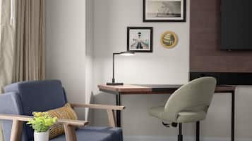 Ett modernt rum med ett skrivbord, två stolar, en lampa, en tv och konstverk på väggen.