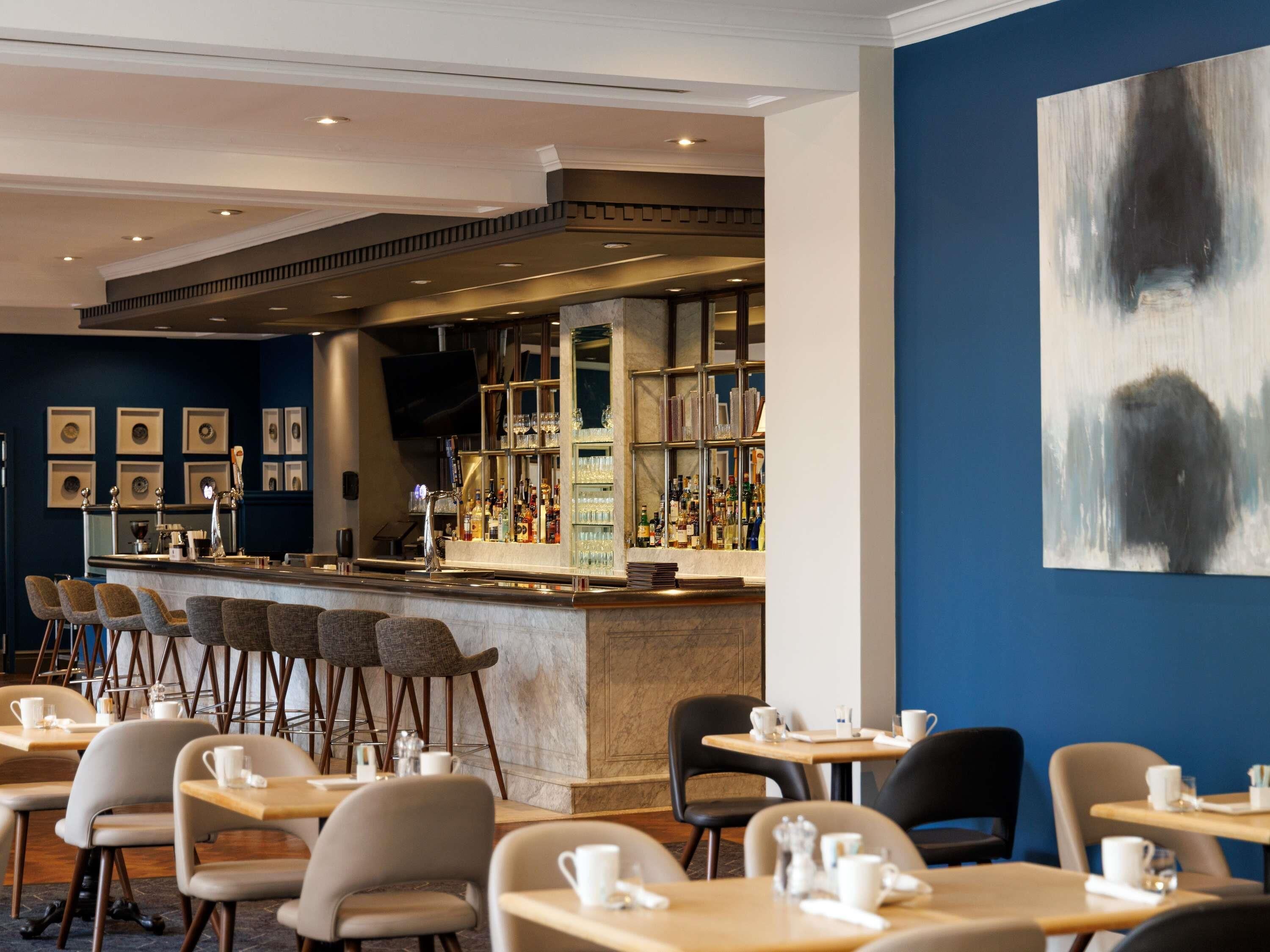 A bar area with a counter, seating, and a large abstract painting on the wall.