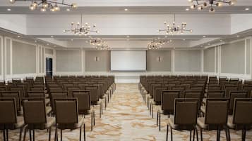 Une salle de conférence avec des rangées de chaises, un sol recouvert de moquette et des lustres.