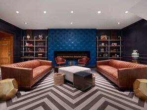 A modern lounge area with leather sofas, a fireplace, and a patterned floor.