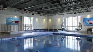 An indoor swimming pool with clear water, a diving board, and two large windows allowing natural light. - Novotel Toronto Centre (Toronto)