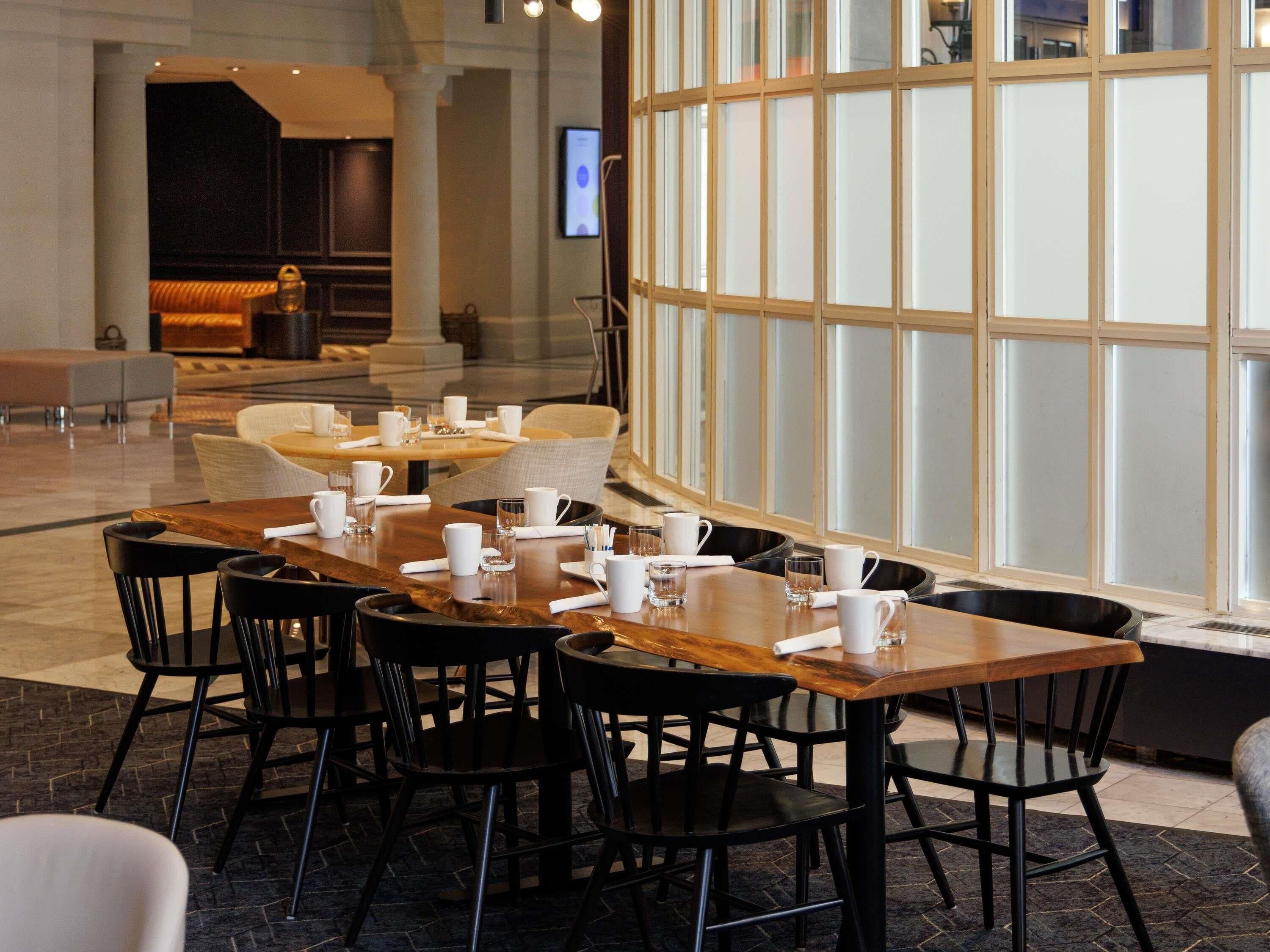 A dining area with tables and chairs, a large window with frosted glass panels, and a seating area with sofas and a coffee table.