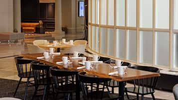 A dining area with tables and chairs, a large window with frosted glass panels, and a seating area with sofas and a coffee table.