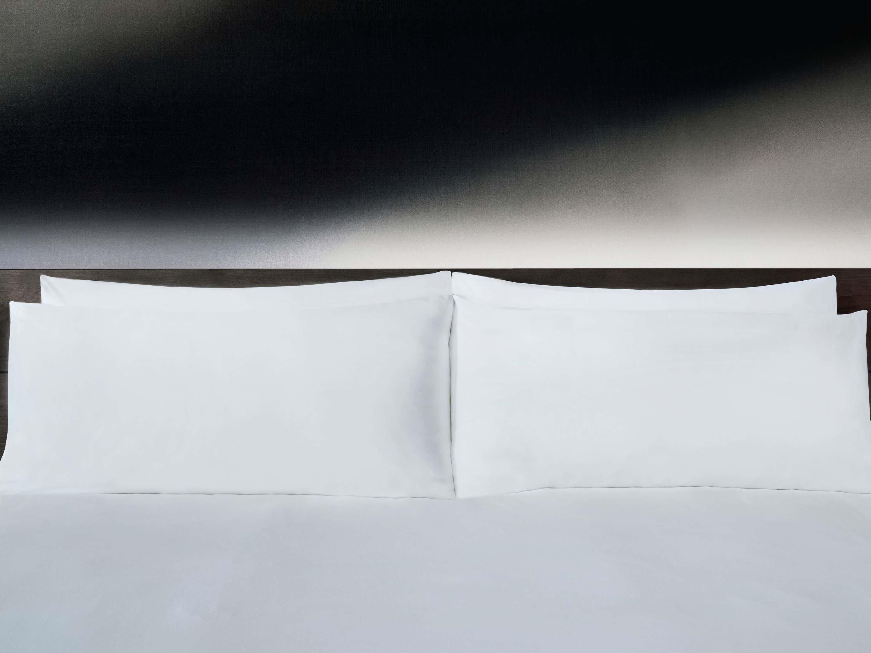 Una cama bien hecha con sábanas blancas y un cabecero oscuro.
