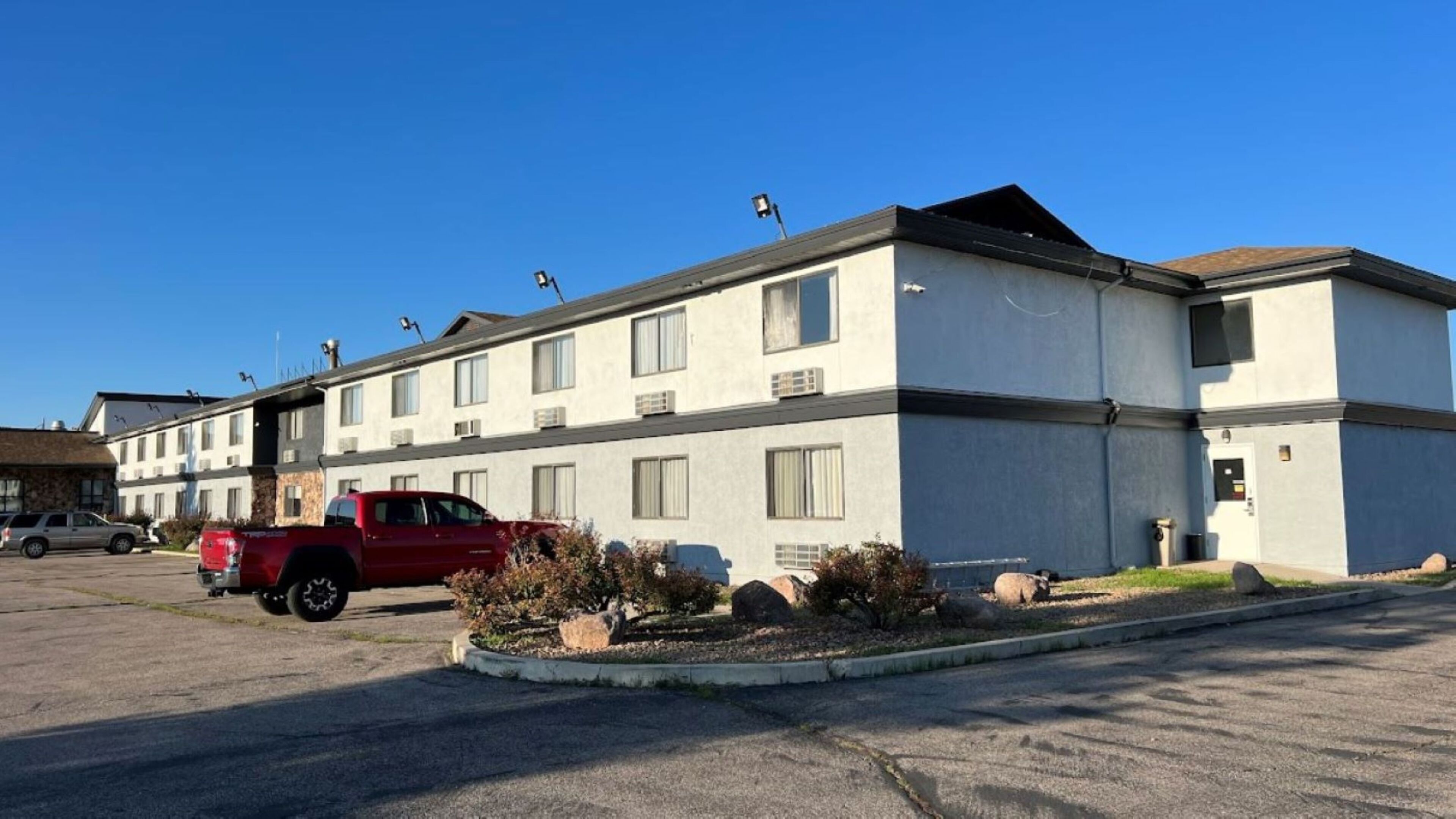 A multi-story motel with a red truck parked in front.