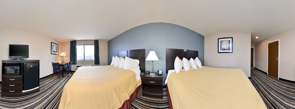 Une chambre d’hôtel avec deux lits, une télévision, un bureau et une fenêtre avec des rideaux.