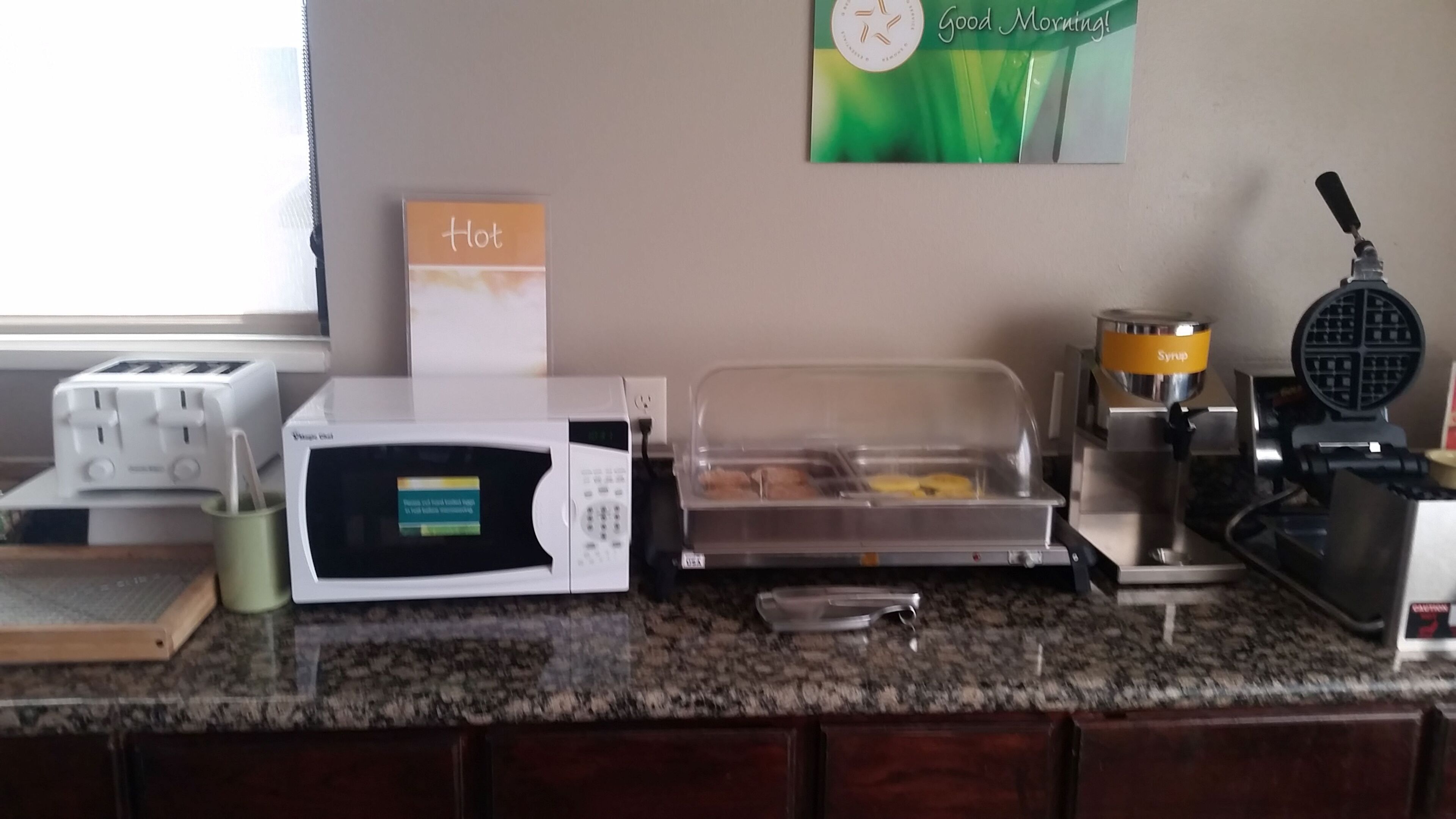 A kitchen counter with a microwave, toaster, and waffle maker.