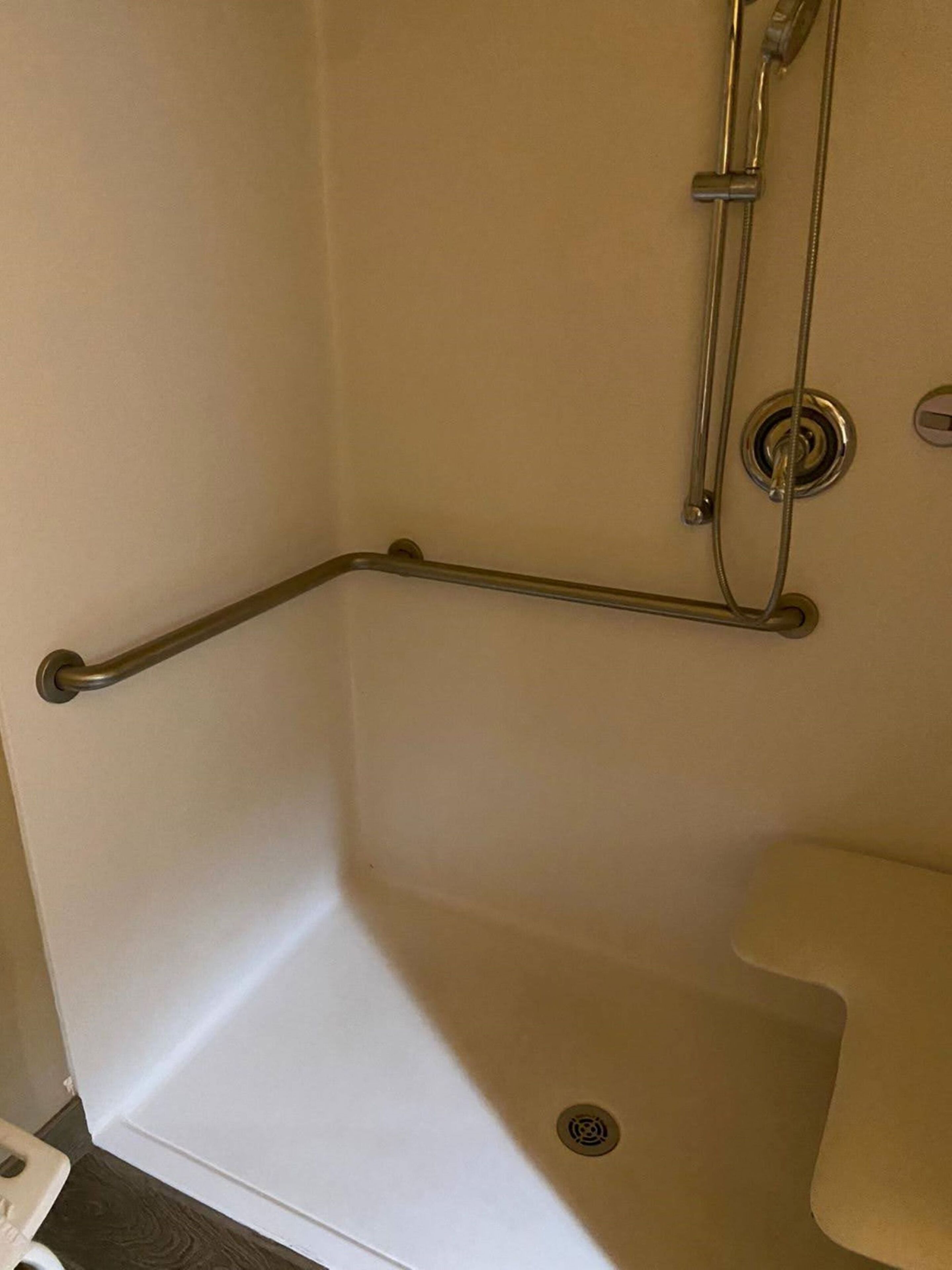 A corner of a bathroom with a shower stall, a grab bar, and a toilet.