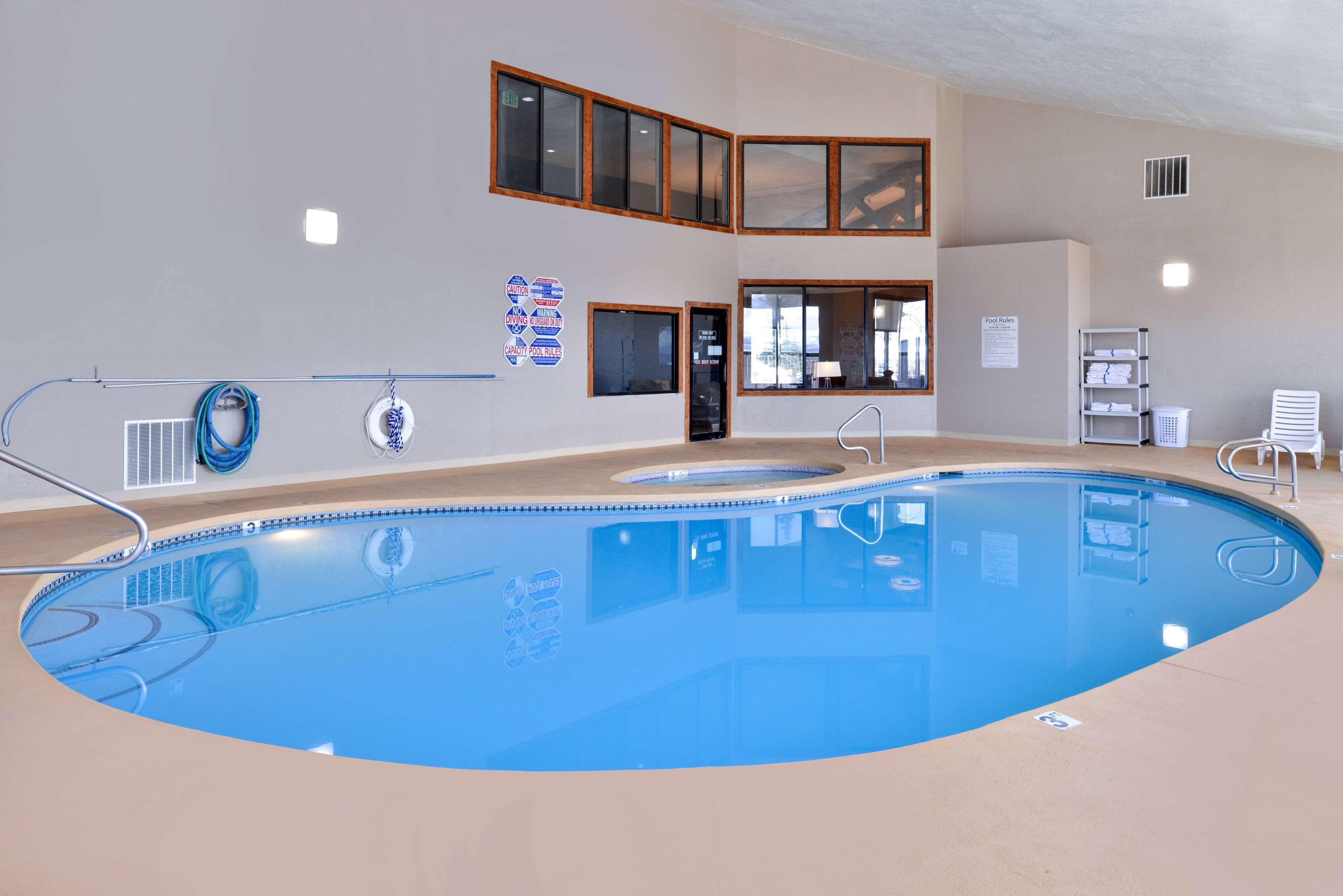 Une piscine intérieure offrant une vue dégagée sur l’espace piscine, dotée d’un système de filtration de l’eau et d’un escalier menant à une porte.
