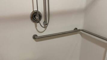 A white shower stall with a grab bar, a white toilet, and a showerhead.
