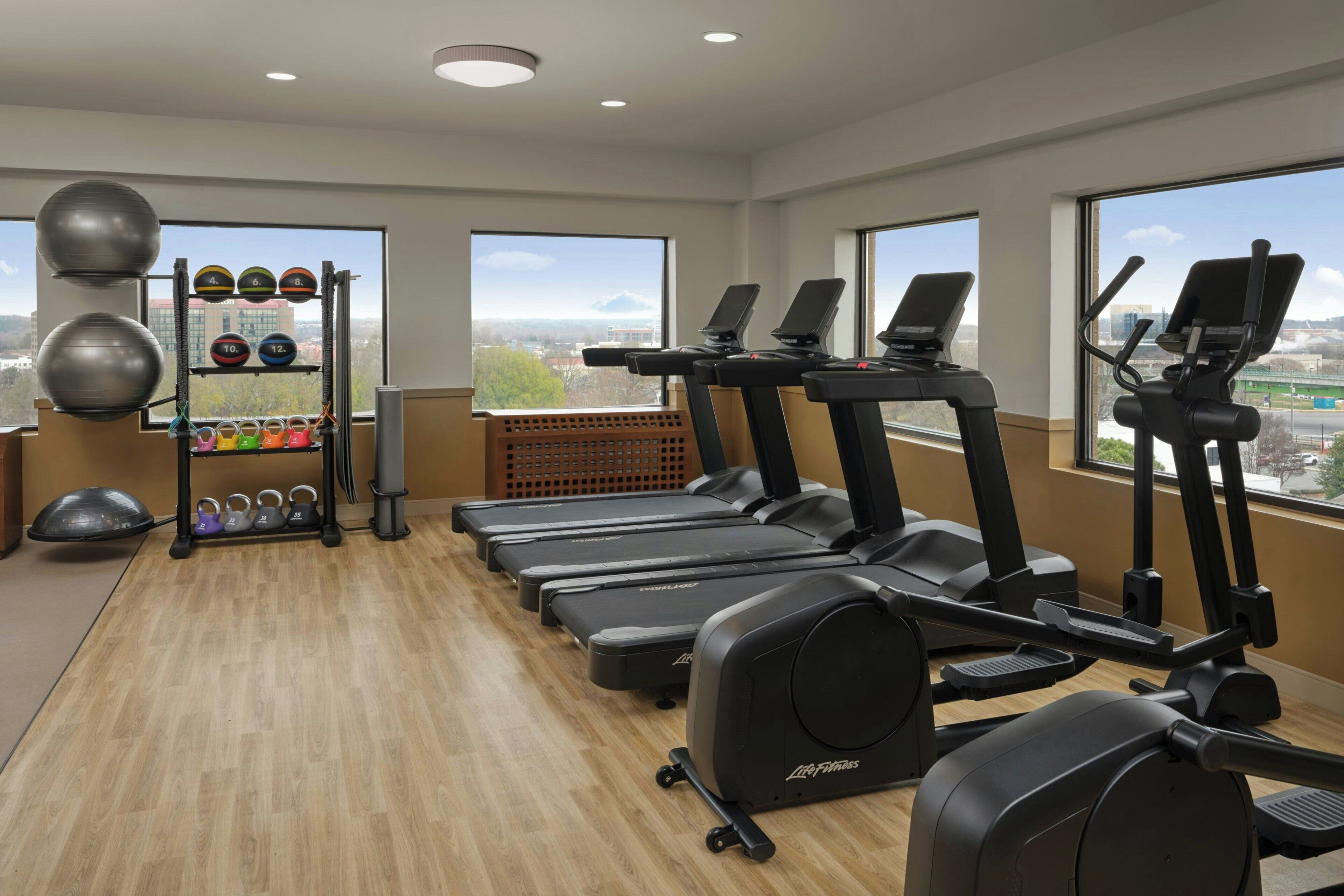 A gym with treadmills, a weight rack, and exercise balls.