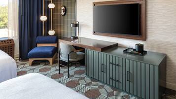 Quarto de hotel com uma cama, uma escrivaninha com cadeira, uma televisão e um armário.