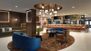 Un interior moderno con zona de bar, asientos y una lámpara decorativa en el techo.