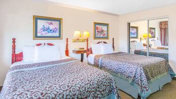 A hotel room with two beds, each with a patterned bedspread, a nightstand with a lamp, and framed artwork on the walls.