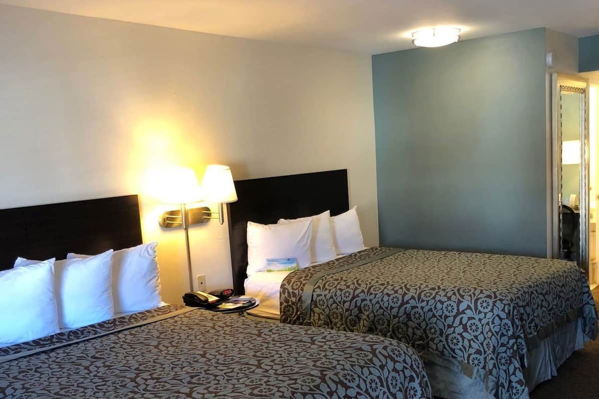 Een hotelkamer met twee bedden, een nachtkastje, een lamp en een deur.