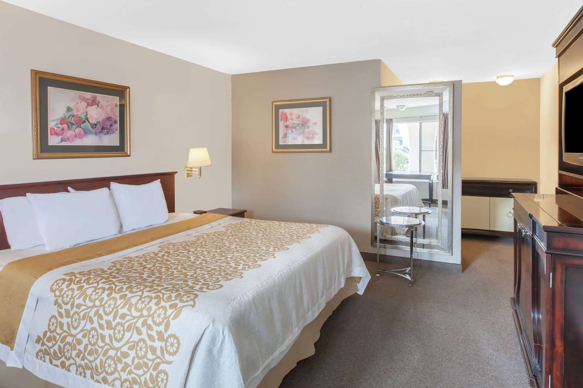 Een hotelkamer met een groot bed, een bureau, een stoel, een televisie en een deur die uitkomt op een balkon.