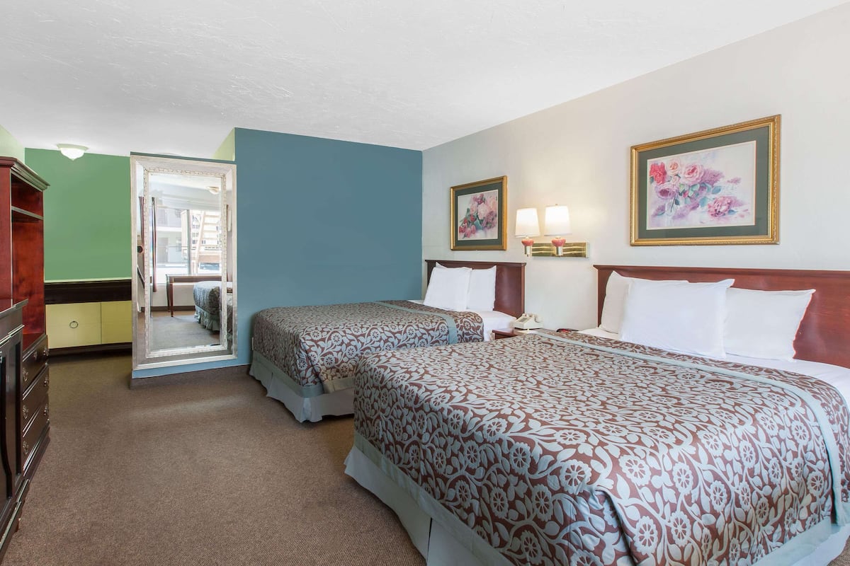 Een hotelkamer met twee bedden, een kaptafel, een spiegel en kunst aan de muur.
