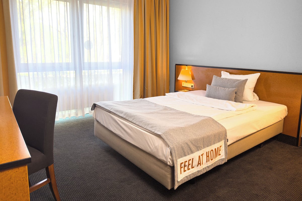 Ein Hotelzimmer mit Bett, Schreibtisch und Stuhl.