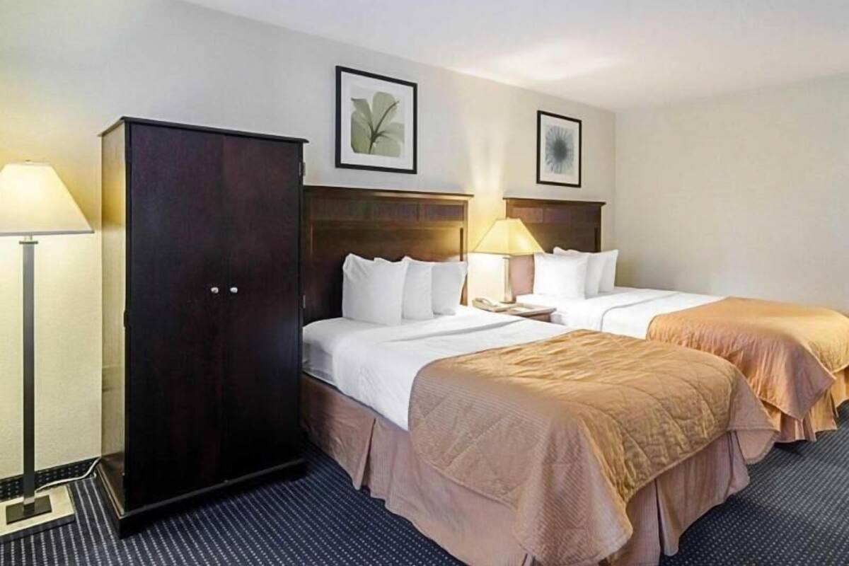 A hotel room with two beds, a wardrobe, and two bedside lamps.