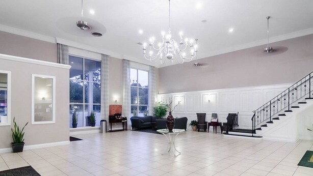 A spacious living area with a chandelier, a staircase, and large windows. - Rodeway Inn & Suites Williamsburg Central (Williamsburg)