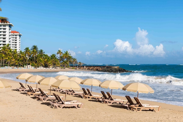 Una playa cerca, arena blanca, sillas reclinables de playa, sombrillas