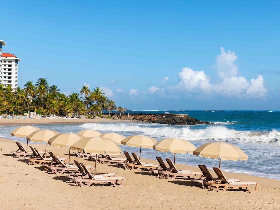 Nær stranden, hvit sand, solsenger og parasoller